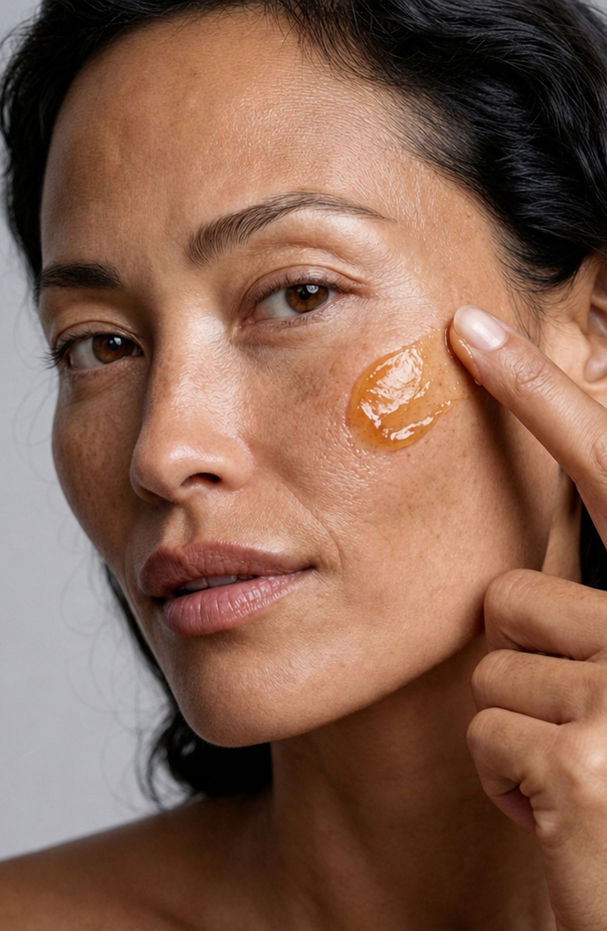 Model smoothing golden OSHAN MOHĀ Beautifying Concrete Gelée onto her cheek.