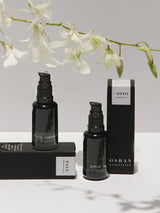 OSHAN Absolute Hydration Set bottles with their boxes and white orchids on marble.