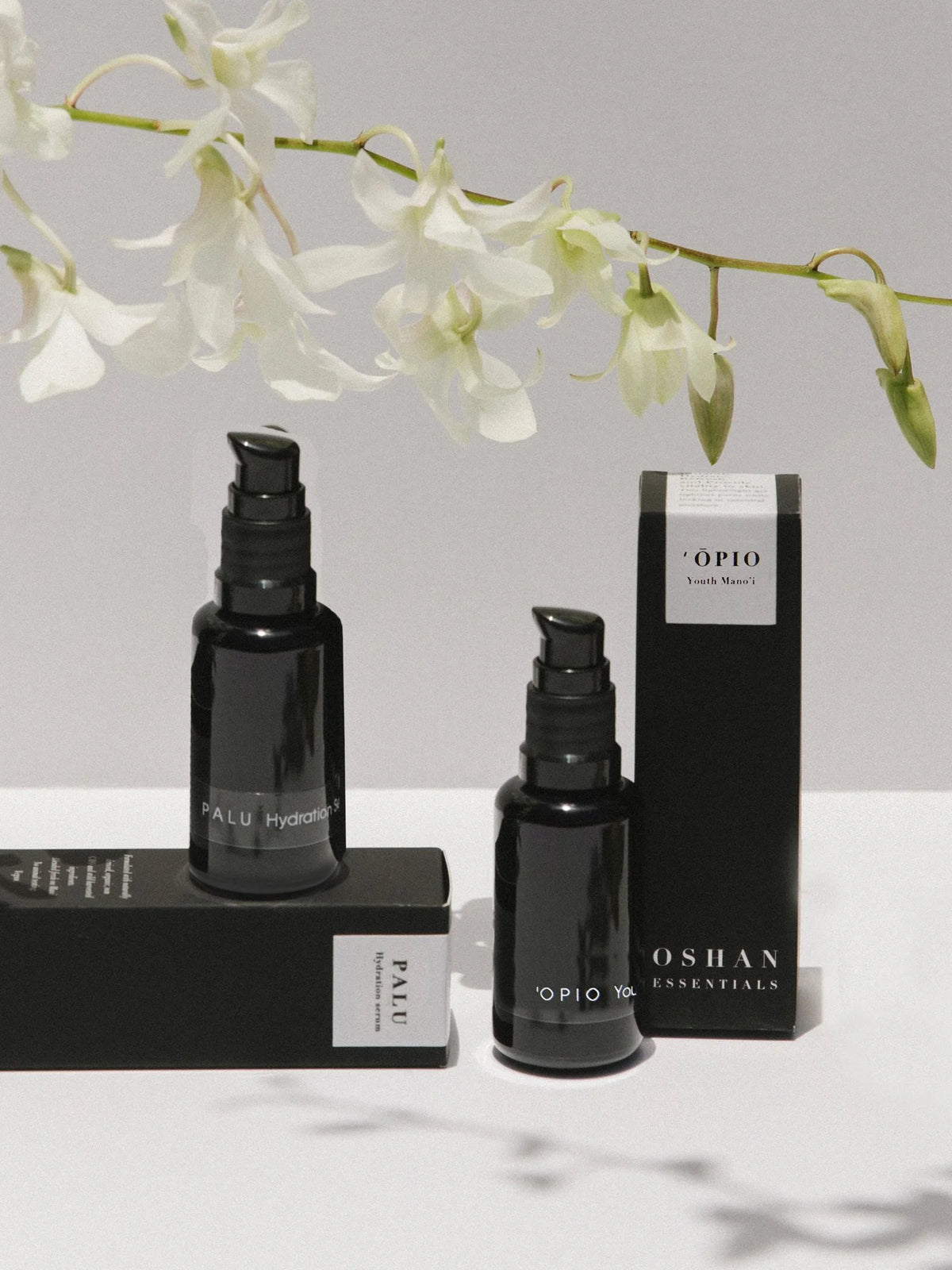 OSHAN Absolute Hydration Set bottles with their boxes and white orchids on marble.