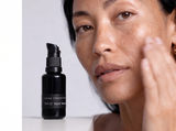 Model pressing ʻŌPIO face oil into damp skin, with the OSHAN Absolute Hydration Set bottle beside her.