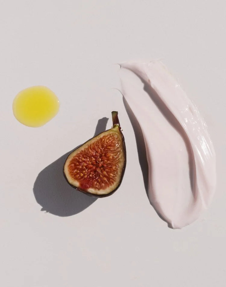 OSHAN ʻĀLANA Radiance Face Soufflé swatch beside a halved fig and a drop of oil.