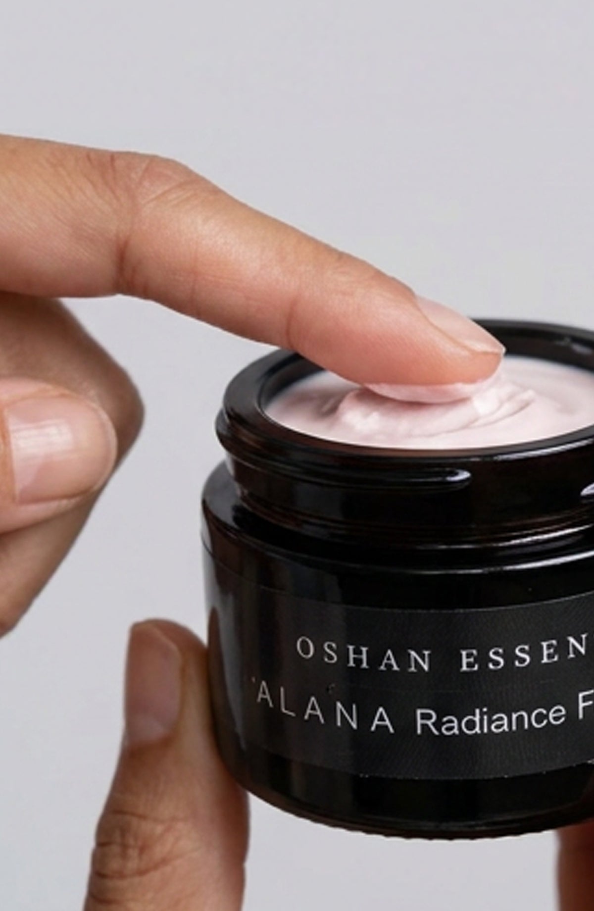 Fingers taking OSHAN ʻĀLANA Radiance Face Soufflé from the open jar.
