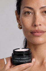 Model holding an open jar of OSHAN ʻĀLANA Radiance Face Soufflé at her chest.