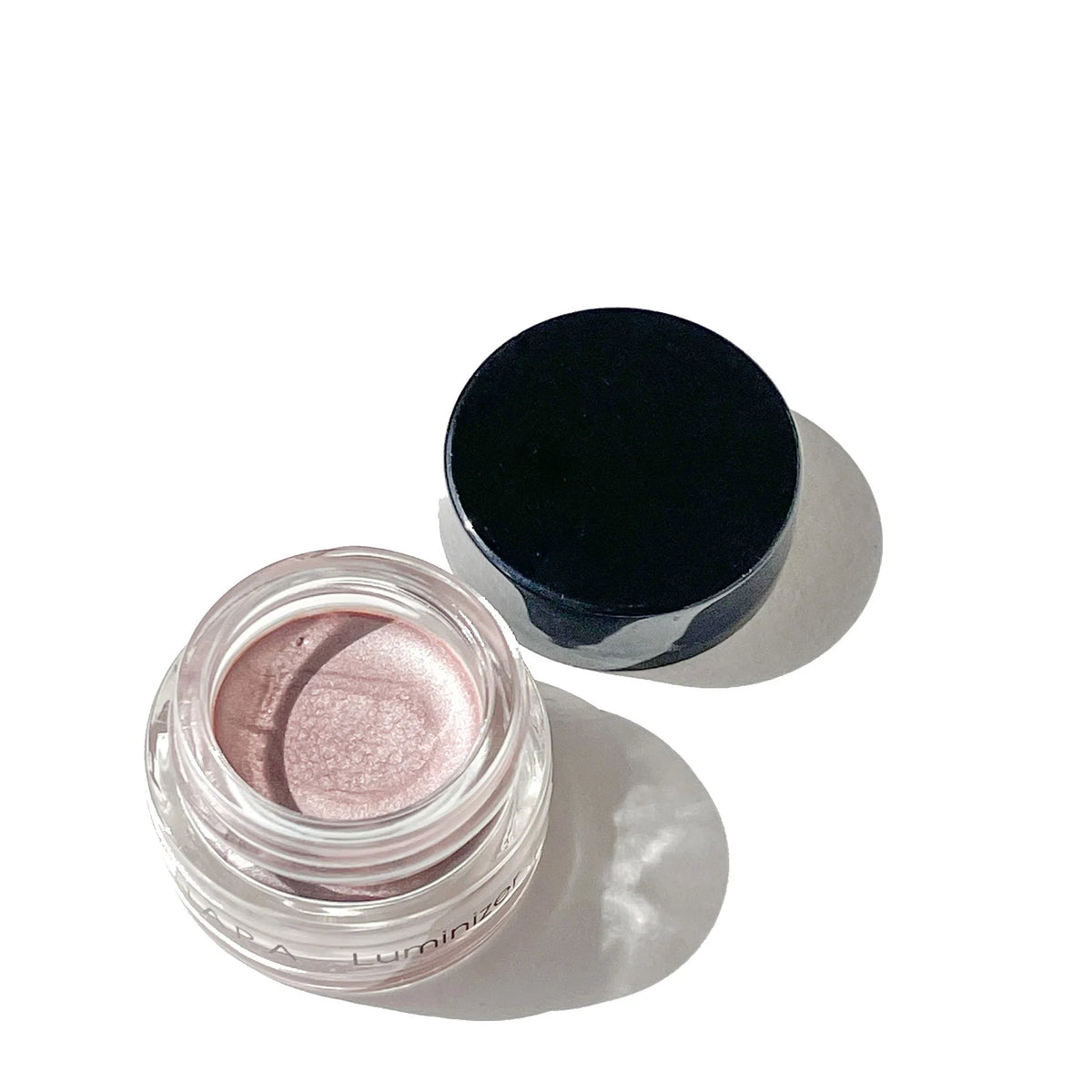 Open jar of OSHAN ʻANAPA Reflective Face Luminizer with its lid beside it.