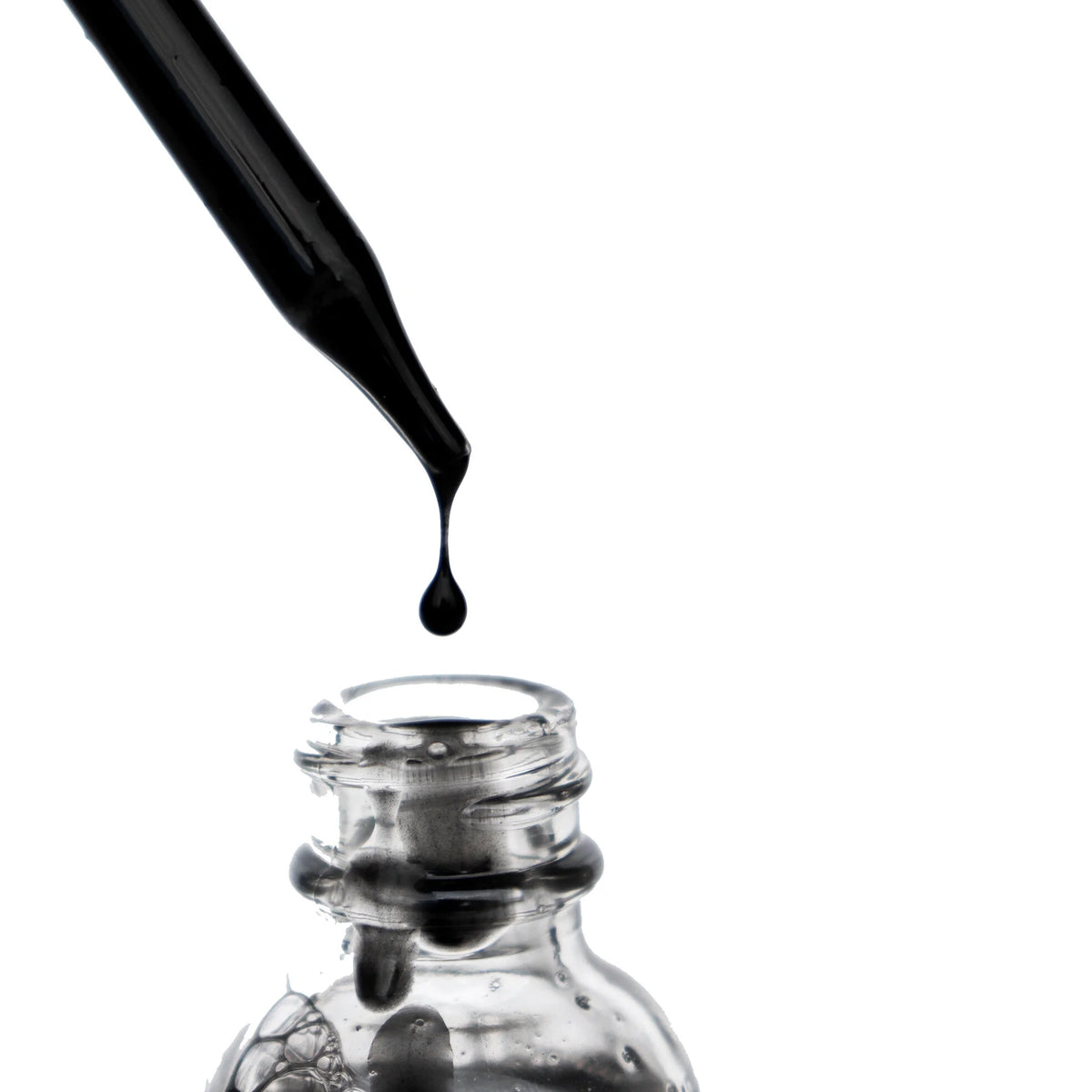 Black ʻELE face wash from the OSHAN BASIC Set pouring into a glass bottle.