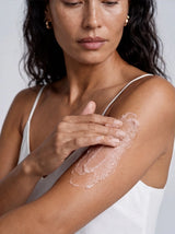 Model smoothing OSHAN CALM ʻĀKALA Body Polish along her upper arm.