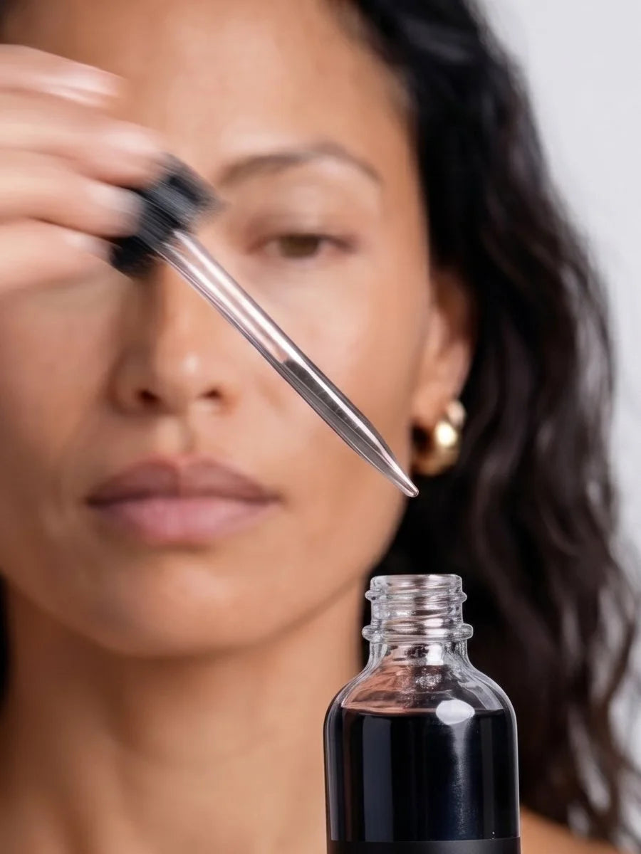 Model holding the dropper of OSHAN ʻELE Clarifying Face Wash to her brow.