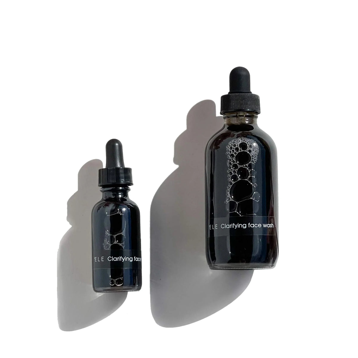 Travel and full size bottles of OSHAN ʻELE Clarifying Face Wash seen from above.