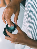 Hands twisting open a jar of OSHAN KAI After Sun Bliss Balm.