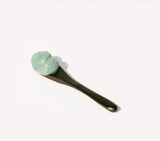 OSHAN KAI After Sun Bliss Balm on a black spatula against a pale background.