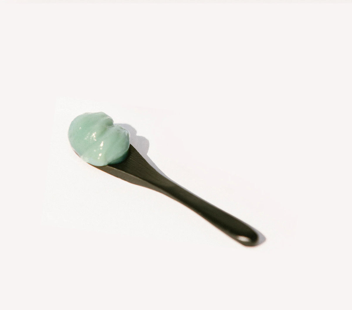 OSHAN KAI After Sun Bliss Balm on a black spatula against a pale background.