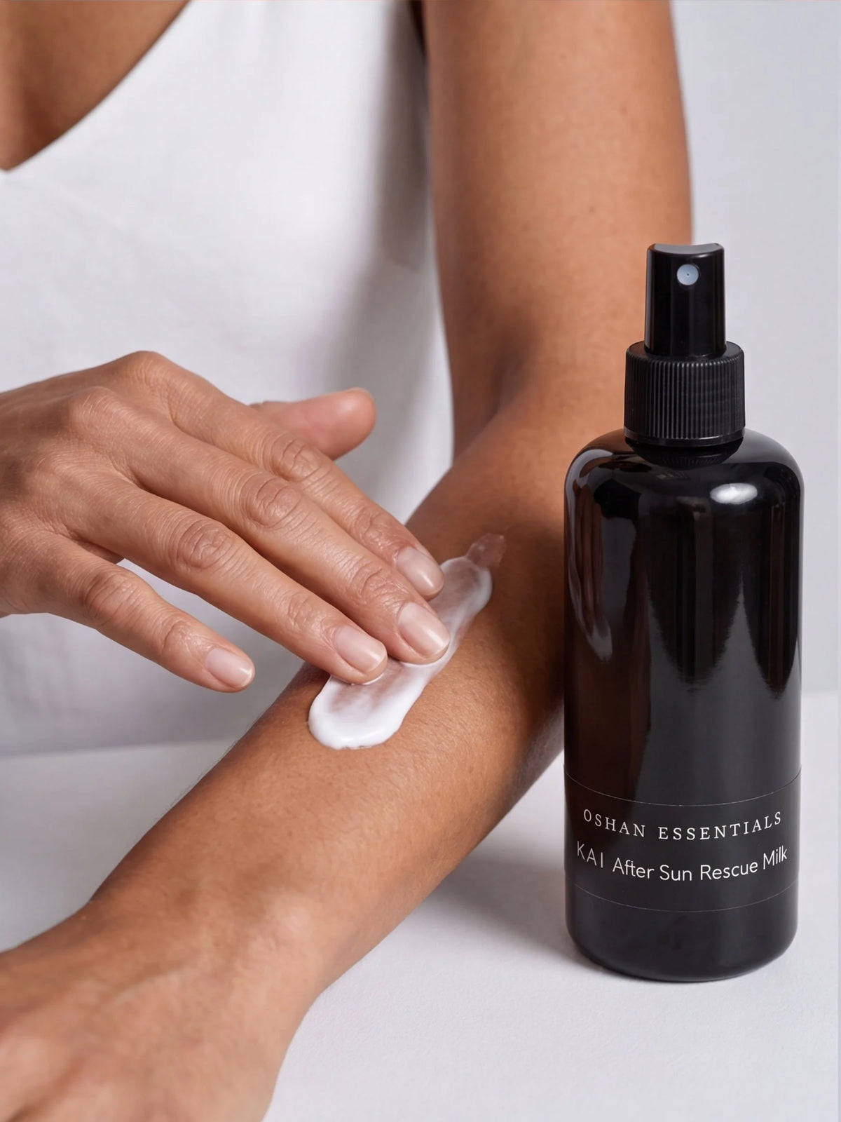 Model smoothing OSHAN KAI After Sun Rescue Milk onto her arm, bottle in hand.