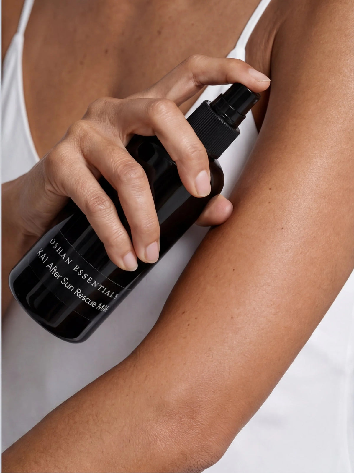 Model spraying OSHAN KAI After Sun Rescue Milk onto her arm.
