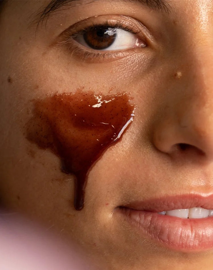 OSHAN KOKIʻO Hydrating Exfoliant spread in a honey coloured patch on a cheek.