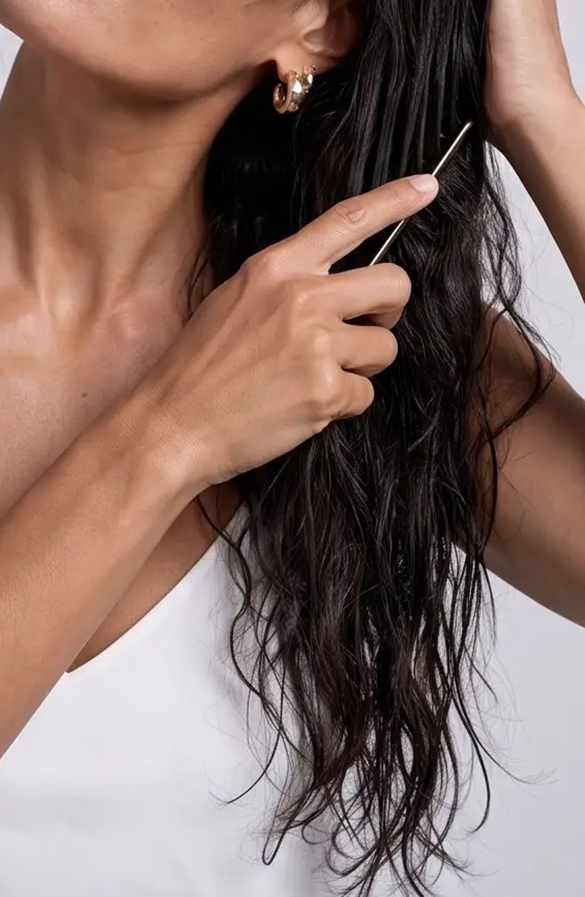 Model combing OSHAN MAIʻA Reviving Leave-In Conditioner through long wet hair.