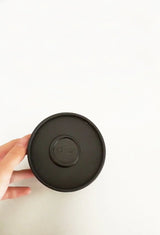 Hand holding the round black box of the OSHAN Mini Facial Ritual Set.