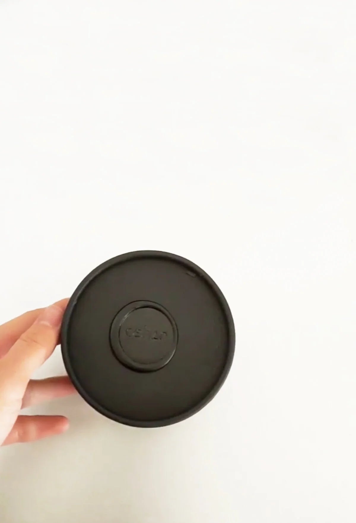Hand holding the round black box of the OSHAN Mini Facial Ritual Set.