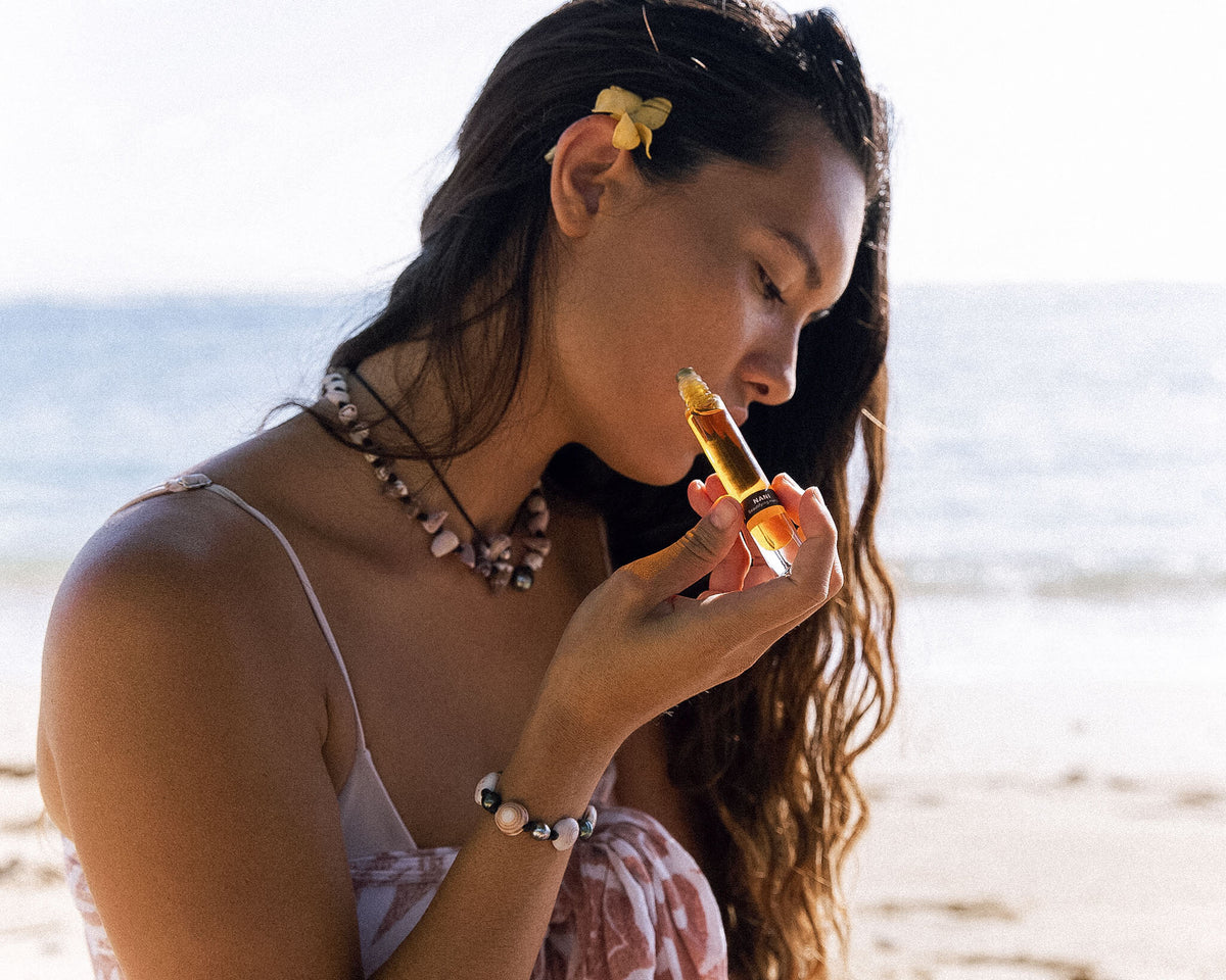 Model at the beach rolling OSHAN NANI Beautifying Manoʻi onto her wrist.