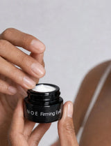Hands opening a jar of OSHAN NOE Firming Eye Cream.