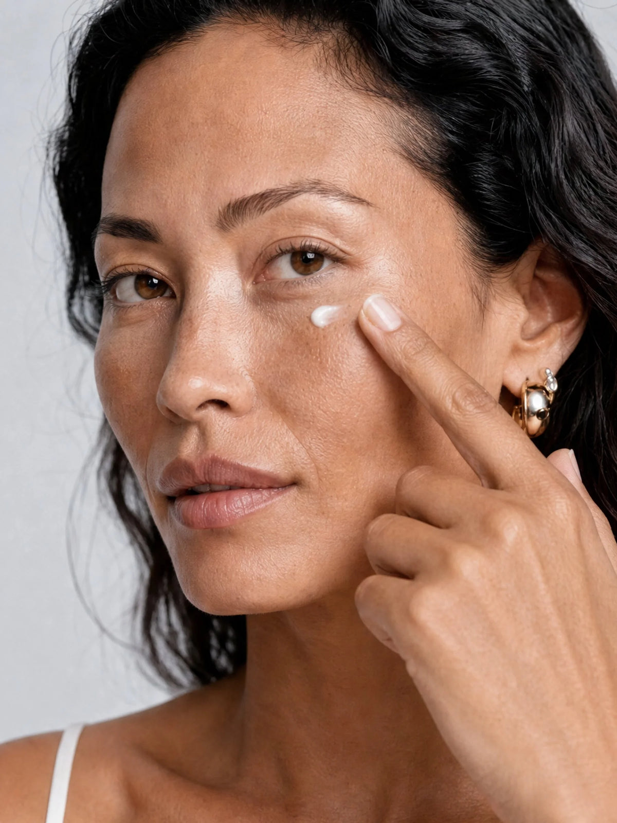 Model patting OSHAN NOE Firming Eye Cream under her eye.