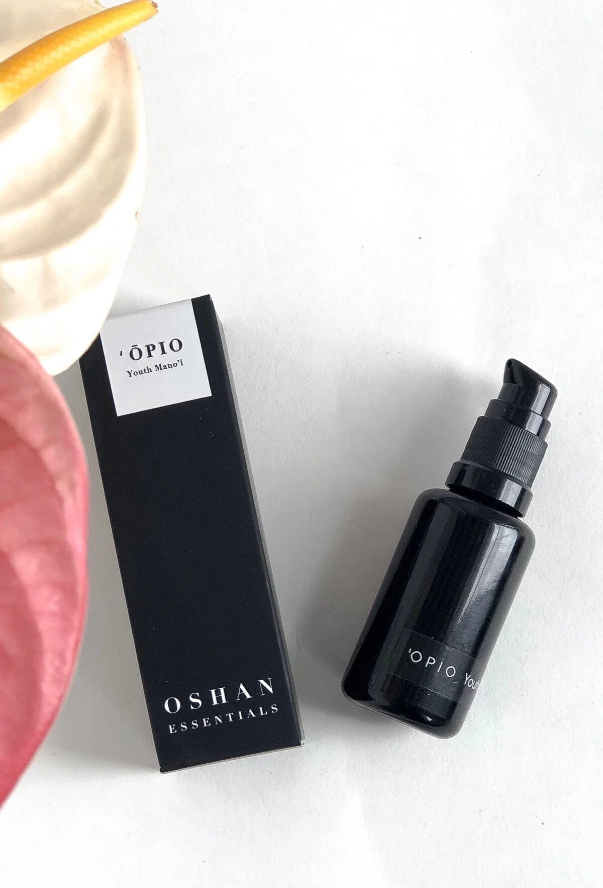 OSHAN ʻŌPIO Youth Manoʻi bottle and box beside a pink anthurium flower.
