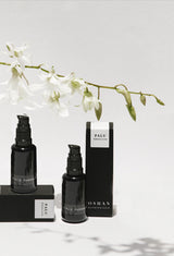 OSHAN PALUPALU Hydration Serum bottles and boxes under a branch of white orchids.