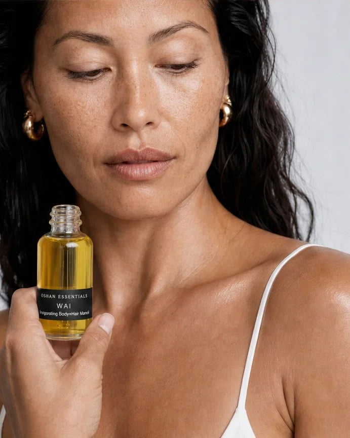 Model holding the OSHAN WAI Invigorating Hair and Body Manoʻi bottle at her collarbone.