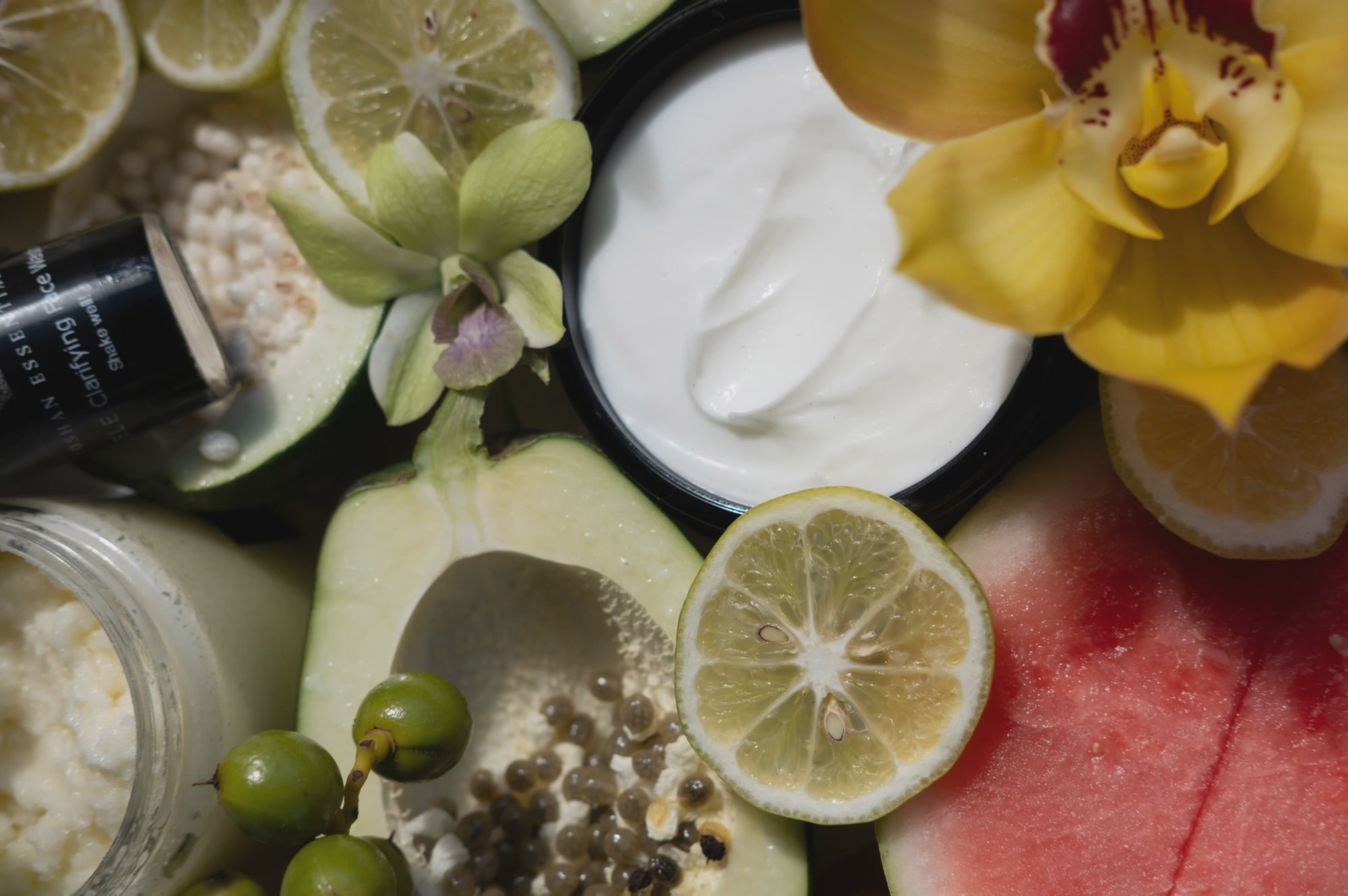Cut limes, watermelon, orchids and open OSHAN jars laid out together